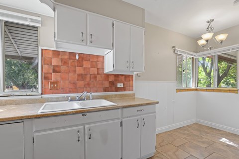 a kitchen with white cabinets and a sink and a window